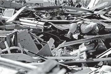  ?? DAVID GOLDMAN/AP ?? A member of a South Florida urban search-and-rescue team sifts through a debris pile for Hurricane Michael survivors.