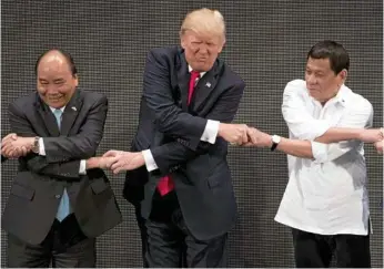  ?? PHOTO: ANDREW HARNIK/AP ?? STRETCHED: US President Donald Trump, centre, seems to be grimacing in pain as he does the “ASEAN-way handshake” with Vietnamese President Tran Dai Quang, left, and Philippine­s President Rodrigo Duterte at the ASEAN Summit in Manila.