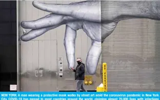  ??  ?? NEW YORK: A man wearing a protective mask walks by street art amid the coronaviru­s pandemic in New York City. COVID-19 has spread to most countries around the world, claiming almost 70,000 lives with infections nearing 1.3 million people. — AFP