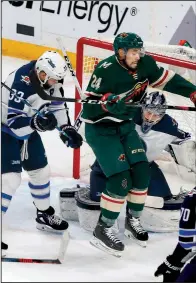  ?? AP/JIM MONE ?? Matt Dumba of the Minnesota Wild jumps for a shot Tuesday night as Winnipeg Jets goalie Connor Hellebuyck (right) looks on during the Jets’ 2-0 victory over the Wild. Winnipeg leads the series 3-1.