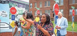  ?? JOURNAL-REGISTER JUSTIN L. FOWLER/THE STATE ?? Gina Latham, center, describes the new mural across the exterior wall of the Route History museum and visitors center city after a ribbon cutting . Next to the mural is a tribute to four important Black entreprene­urs in Springfield, two of whom were killed in the 1908 Springfield Race Riot.