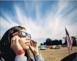  ??  ?? EATING MYTHS involving the eclipse abound, with wolves and dragons among those taking a bite out of the sun. Above, Sofija Miranda, 11, tries out her glasses.