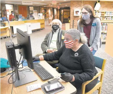  ?? PAUL W. GILLESPIE / CAPITAL GAZETTE ?? Frances Smith and former Judge Robert M. Bell get help from library assistant Amy Yonts. Smith and Bell use a computer at the EastportAn­napolis Neck Library Friday for a Zoom meeting with Smith’s husband, William “Smitty” Smith Jr., who suffered two strokes and is bedridden in the Charlotte Hall Veteran’s Home in St. Mary’s County.