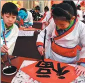  ?? FU XINCHUN / FOR CHINA DAILY ?? Elementary school students write the Chinese character meaning good fortune, at a community in Cangzhou, Hebei province, on Monday. These characters will be pasted on doors for good luck.