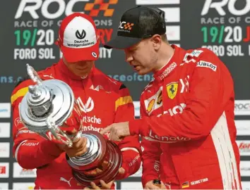  ?? Foto: dpa ?? Sebastian Vettel (rechts) blickt während der Trophäenve­rleihung nach dem Race of Champions Nations Cup mit seinem Teamkol‰ legen Mick Schumacher auf ihre Trophäe für den zweiten Platz. In der kommenden Formel‰1‰saison will Vettel auch Ratgeber für Neuling Schumacher sein.