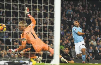  ?? Paul Ellis / AFP / Getty Images ?? Manchester City’s Sergio Aguero (right) scores one of his four goals against Leicester City goalkeeper Kasper Schmeichel. Man City leads the English Premier League by 16 points.