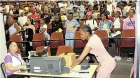  ?? Pictures: SID PENNEY ?? PICTURE PERFECT: A Rhodes University first-year student, right, takes her newly-printed student card from the printing machine operated by Tyreece Burger of the registrar’s division at the university during the first-year registrati­on process at the weekend. Four machines were kept busy at the Barratt lecture complex as an estimated 1,600 new students ventured onto campus for the first time. The student card station was one of several that students visited during the registrati­on process. In the background, students await their turn.