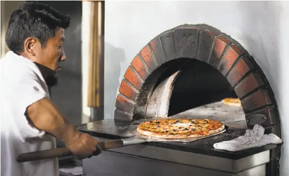  ?? PHOTOS BY LAURA MORTON ?? Pizza is made in a wood-fired oven at East End, a bistro located in Alameda Marketplac­e. Pizzas can be purchased par-baked, so customers can finish cooking them at home.