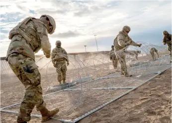  ?? BRANDON BELL/GETTY IMAGES ?? Texas National Guard soldiers install border fencing layered with concertina wire near the Rio Grande River on April 2 in El Paso.