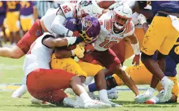 ?? KARL B DEBLAKER/AP ?? East Carolina’s Keaton Mitchell (2) is wrapped up by North Carolina State’s Travali Price (58), Drake Thomas (32) and Tanner Ingle on Saturday in Greenville, N.C.