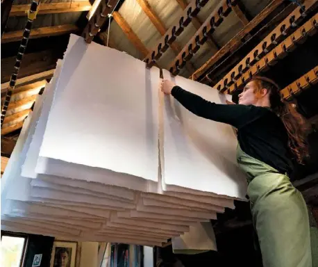  ??  ?? Chloe hangs paper from racks across the ceiling in the drying attic, after sizing. Paper samples in varying shades, including sheets with real flowers embedded in the surface to add texture and interest.