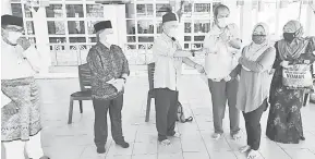  ??  ?? SAMPAIKAN: Talib (tiga kiri) menyampaik­an sumbangan kepada seorang penerima sambil disaksi Haidar, Penghulu Drahman (kiri) dan yang lain.