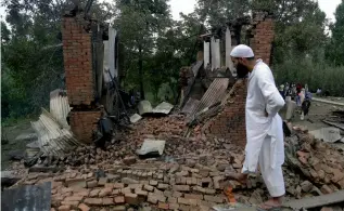  ?? — AP ?? A Kashmiri Muslim villager looks at the debris of one of the damaged houses after a gunbattle at Bahmnoo village 58 km south of Srinagar, Kashmir recently