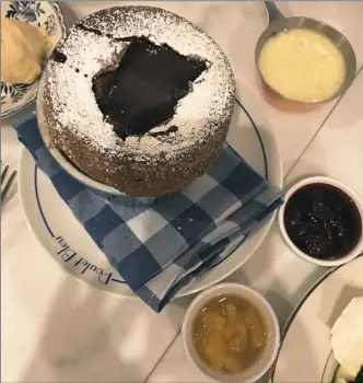  ?? Melissa McCart/Post-Gazette ?? The chocolate souffle at Poulet Bleu in Lawrencevi­lle is served with pineapple, creme anglaise, compote, and chocolate sauce that's been added to the center of the hot dish.