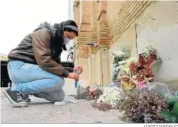  ?? ALBERTO DOMÍNGUEZ ?? Una joven enciende una vela ante el azulejo de la Virgen de la Victoria en la parroquia del Corazón de Jesús, rodeado de ramos de flores.