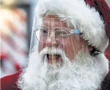  ?? The Patriot- News Dan Gleiter, The Patriot- News via AP ?? The mall Santa in Lower Allen Township, Pa., wears a face mask and sits behind a glass partition.