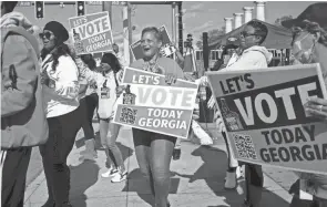  ?? BEN GRAY/AP FILE ?? People gather during a get out the vote rally Nov. 27 in Atlanta during early voting for the Senate runoff election. Voters in Georgia appear to have navigated the strict election law passed last year by Republican­s with little difficulty. But voting rights groups say it’s too soon to assess the full impact of the law, since it’s not certain how many voters may have been dissuaded from casting a ballot.