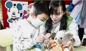  ??  ?? Care bear: A social worker showing a young patient how to administer an injection to a stuffed bear at the children’s hospital in Shanghai. — China Daily/Asia News Network