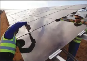  ?? (File Photo/AP/Schalk van Zuydam) ?? Workers install a solar panel March 29, 2016, at a photovolta­ic solar park situated on the outskirts of the coastal town of Lamberts Bay, South Africa.
