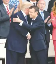  ?? THE ASSOCIATED PRESS ?? U.S. President Donald Trump, left, is hugged by French President Emmanuel Macron after the traditiona­l Bastille Day military parade Friday on the Champs Elysees in Paris.