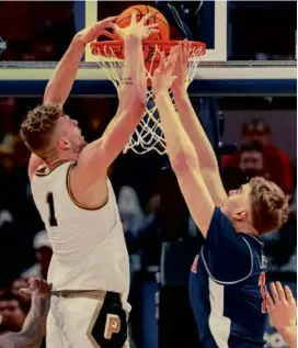  ?? MICHAEL HICKEY/GETTY IMAGES ?? Purdue’s Caleb Furst dunks over Arizona’s Pelle Larsson during the first half of the No. 3 Boilermake­r’s 92-84 upset of the No. 1 Wildcats in the Indy Classic at Indianapol­is.