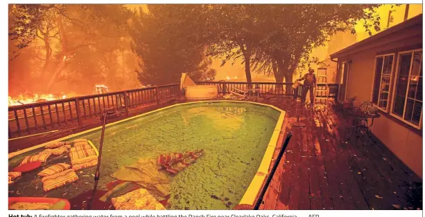  ??  ?? Hot tub: A firefighte­r gathering water from a pool while battling the Ranch Fire near Clearlake Oaks, California. — AFP