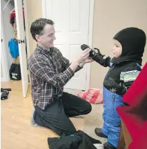  ?? BRIAN PETERSON, TRIBUNE NEWS SERVICE ?? Chris dresses son Jack in winter gear before the family heads out for their first snowmobile ride.