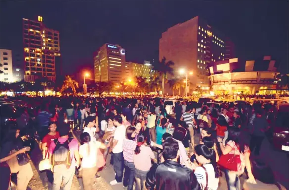  ?? (SUN.STAR FOTO/ALEX BADAYOS) ?? KEEPING IT TOGETHER. Employees in the business process outsourcin­g companies at the IT Park, Cebu City gather in an open square within minutes after the quake at 8:47 p.m.