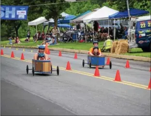  ?? MARIAN DENNIS – DIGITAL FIRST MEDIA ?? In a fun race down Wilson Street during the Soap Box Derby Saturday, adults accompanie­d kids in the cars.