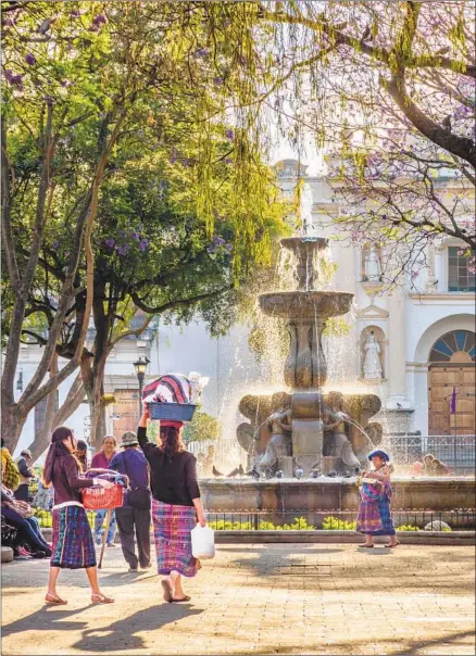  ?? Lucy Brown Getty Images ?? LOCALS, vendors and tourists tend to their business on a morning in March 2018 in Plaza Central, the heart of Antigua, Guatemala.