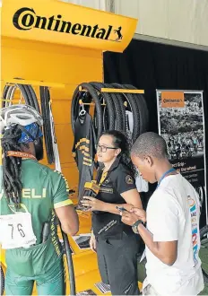  ??  ?? EXPERT HELP: Megan Earl, of Continenta­l Bicycle Tyres, provides some bike tyre advice to Imveli Cycling Academy rider Vincent Dogbey Wornameh, left, and fomer Digital Content Developer of Good News Lab, Siya Ndzimande. Continenta­l Tyre SA will once...