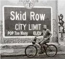  ?? Frederic J. Brown / AFP via Getty Images ?? A cyclist rides past a Skid Row sign in Los Angeles on Monday. The author notes California ties Oregon for third place in its per capita homeless rate.