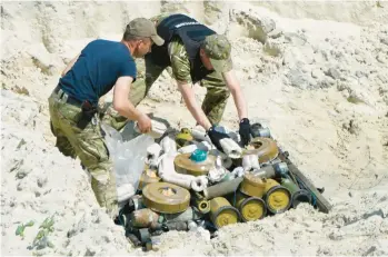  ?? NATACHA PISARENKO/AP ?? Ukrainian soldiers prepare to detonate a cache of unexploded Russian ordnance Wednesday in Kyiv.