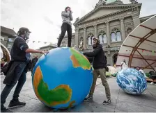  ?? — AFP ?? Making a stand:
A climate activist standing on an inflatable globe and shouting in front of the Swiss House of Parliament in Bern.