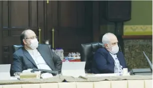  ?? (Reuters) ?? IRANIAN FOREIGN MINISTER Javad Zarif (right) wears a face mask amid fears of coronaviru­s as he attends a government task force meeting on its spread in Tehran last week.