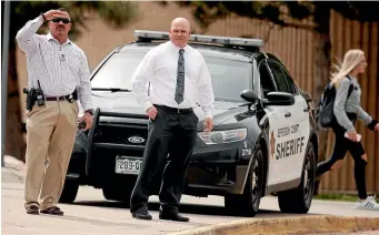  ?? AP ?? Columbine High School principal Scott Christy, right, joins an officer in watching as students leave the school yesterday in Littleton, Colorado.