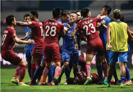  ?? AFP PIC ?? A brawl erupting between Shanghai SIPG players (in red) and Guangzhou R&F players (in blue) as Shanghai’s Oscar lies on the ground in their Chinese Super League match on Sunday.