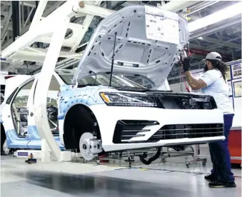  ?? STAFF FILE PHOTO BY ERIN O. SMITH ?? Volkswagen employees work on vehicles in August 2017 at the Volkswagen plant.