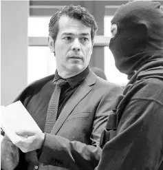  ??  ?? Ursache (left) presents the constituti­onal law to a policeman as he arrives for the opening of his trial at the district court of Halle/Saale. — AFP photo