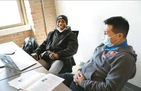  ?? CHRIS SWEDA/CHICAGO TRIBUNE ?? Jermal Ray, 17, left, laughs with mentor Luis Sinchi as Ray works on crafting a presentati­on on a mental health report at Communitie­s United in Chicago on Feb. 19, 2022. The report focused on the mental health and well-being of young Black and brown men in Chicago.