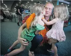  ?? DARRYL DYCK/THE CANADIAN PRESS ?? Burnaby firefighte­r Brad Dairon, centre, is greeted by his daughters Abigail, left, 7, and Olivia, 5, after he returned home from a volunteer mission in Nepal searching for survivors of the April 25 earthquake.