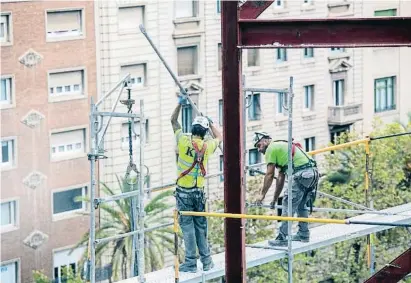  ?? MANÉ ESPINOSA ?? Dos obreros colocan un andamio en una obra en Barcelona