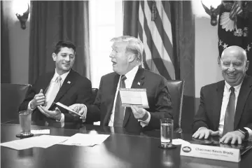  ??  ?? President Donald Trump, flanked by Speaker of the House Republican Paul Ryan, and chairman of the House Ways and Means Committee Republican Brady holds an example of what a new tax form may look like during a meeting on tax policy with Republican law...