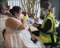  ?? RICHIE STEVER/UNIVERSITY OF MARYLAND MEDICAL SYSTEM ?? Sarah Studley decided the dress for her pandemic-postponed wedding reception was not going to go to waste as she wears it to her first coronaviru­s vaccinatio­n appointmen­t April 11 at M&T Bank Stadium in Baltimore.