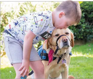  ??  ?? Charlie Galligan gives his guide dog Iona a kiss.