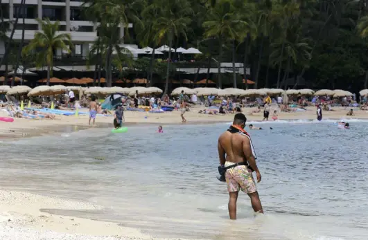  ?? Caleb Jones, The Associated Press ?? A man stands on a crowded Waikiki Beach in Honolulu on Monday. With COVID-19 cases climbing, Hawaii has the second highest infection rate of any state.