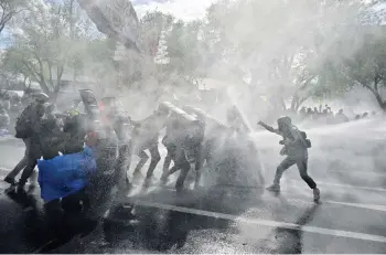  ?? — Photo by Lillian Suwanrumph­a / AFP ?? Pro-democracy protesters confront riot police whilst marching to Government House to call for the resignatio­n of Prime Minister Prayut.