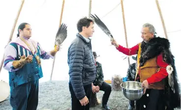  ?? — THE CANADIAN PRESS ?? Justin Trudeau receives a water cleansing by spiritual leader Cecil Grinder and chiefs of the Tsilhqot’in National Government Friday near Chilko Lake, where the prime minister apologized for the hanging of six chiefs in 1864.