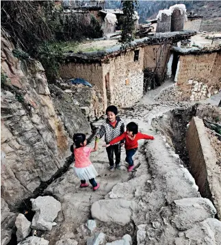  ??  ?? Tres niños juegan en la aldea antigua de Chengzi, en el distrito de Luxi, provincia de Yunnan.