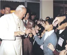  ??  ?? Juan Pablo II saluda a un grupo de niños a poco de su arribo en el entonces aeropuerto internacio­nal Presidente Stroessner.